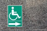 Confusing signage with International Symbol of Access wheelchair sign, in green with arrow. Is this an exit, entrance or toilet?