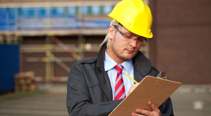 Building Professional Taking Site Notes on Site, wearing a yellow hard hat