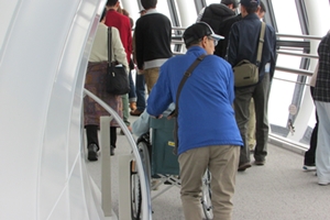 Elderly person in wheelchair being pushed up ramp at tourist Skytree observation tower in Tokyo
